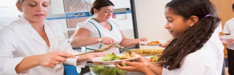 A girl is receiving a plate of food from a woman
