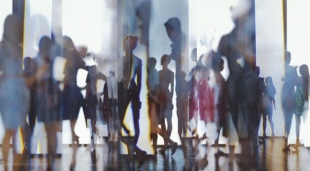 Blurred image of many people in an enclosed work environment. 